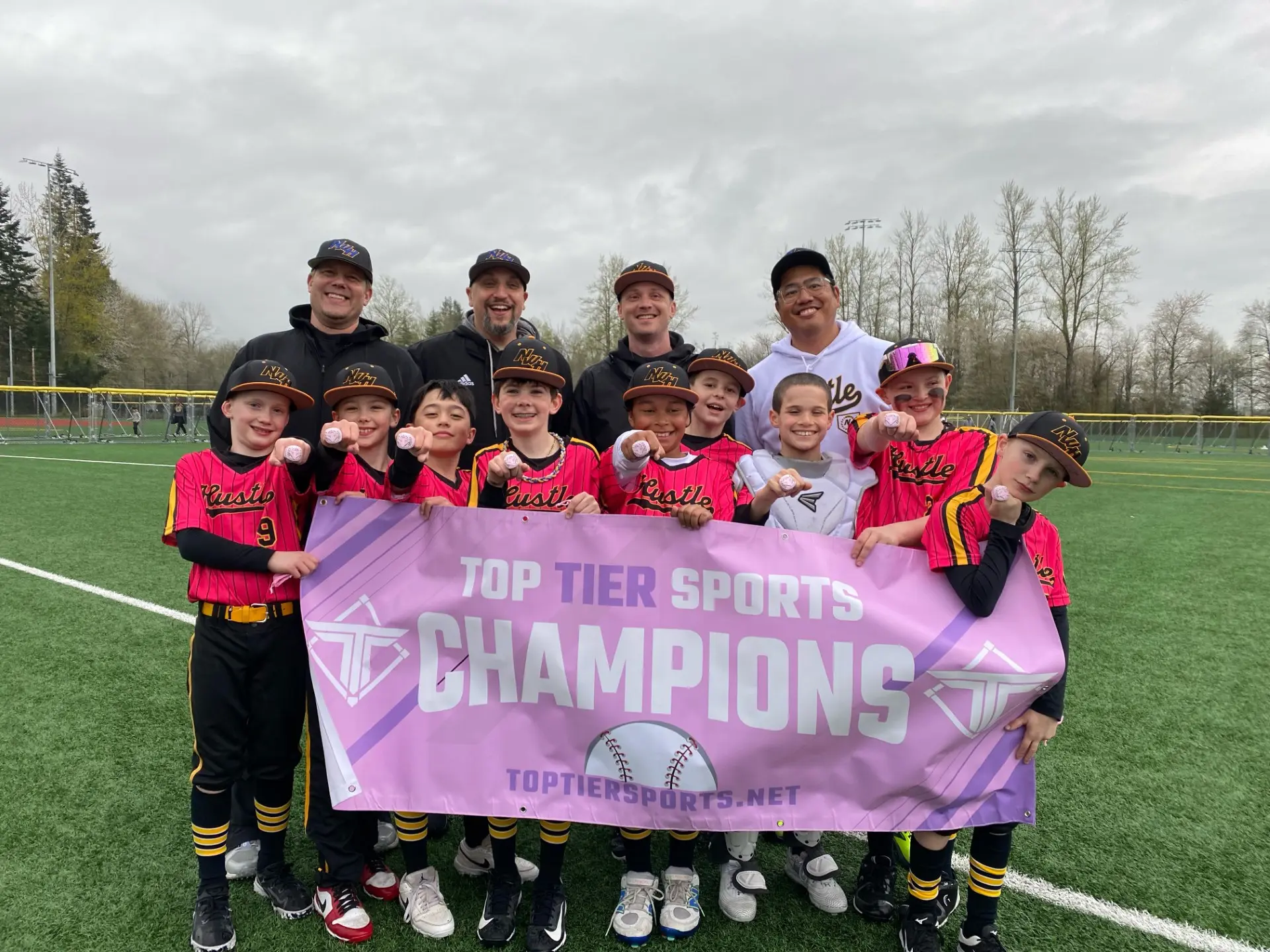 Team displays championship rings and a banner on a green baseball field, highlighting their success.